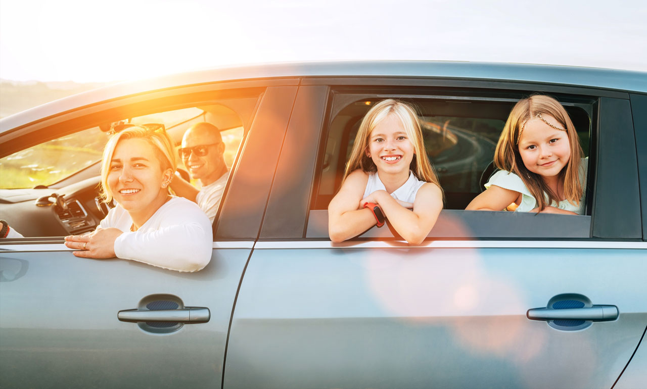 Happy,Young,Couple,With,Two,Daughters,Inside,Car,During,Auto